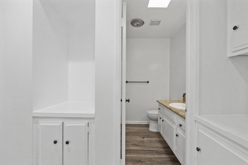 a bathroom with white walls and a wooden floor