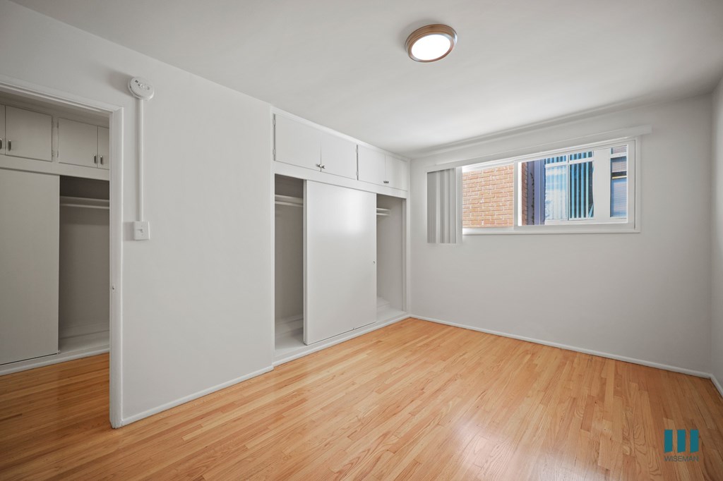 Bedroom with Closet, Cabinet Storage, and Hardwood Flooring