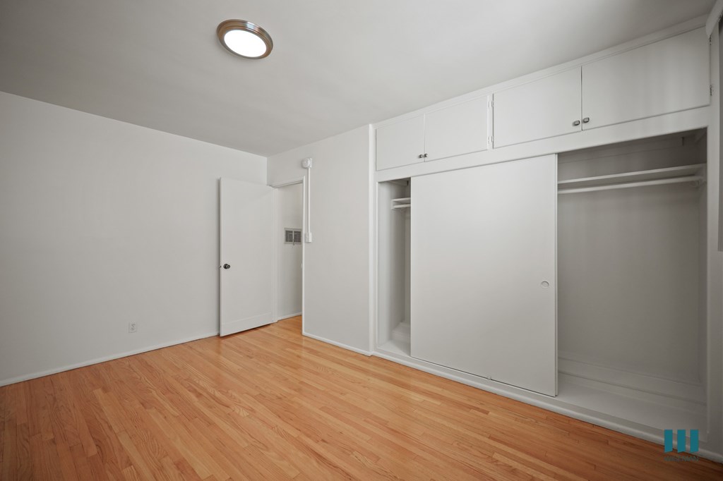 Bedroom with a Large-Size Closet, Cabinet Storage, and Hardwood Flooring
