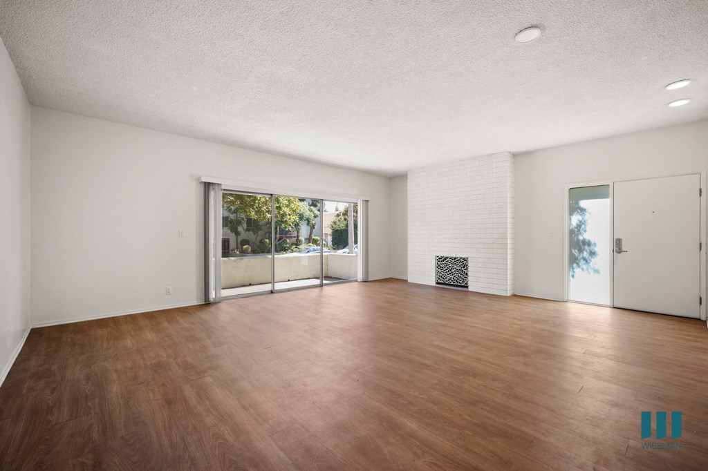an empty living room with wood floors and a sliding glass door