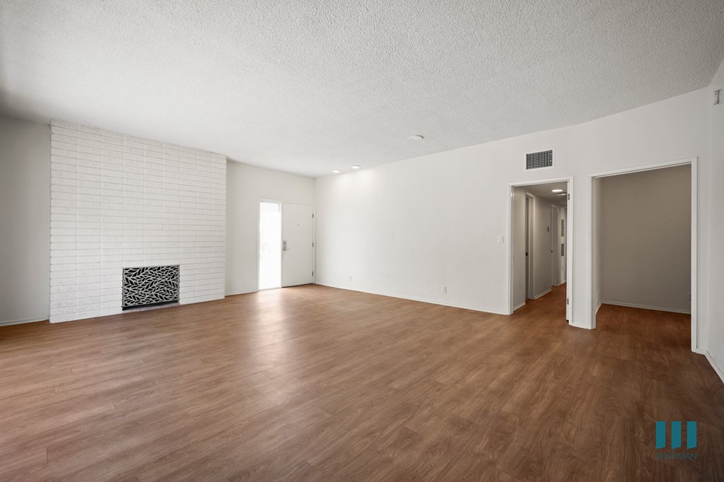 an empty living room with wood flooring and a fireplace