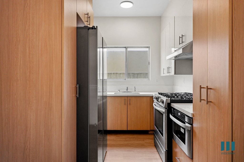 a kitchen with wood cabinets and stainless steel appliances and a refrigerator
