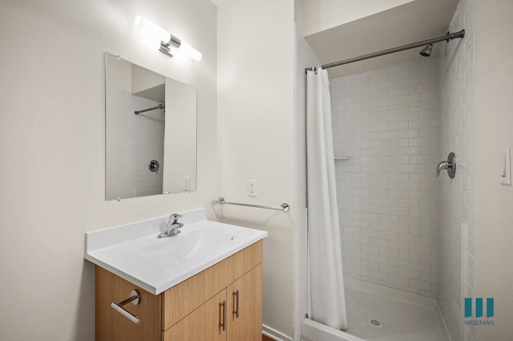 a bathroom with a sink and a shower and a mirror