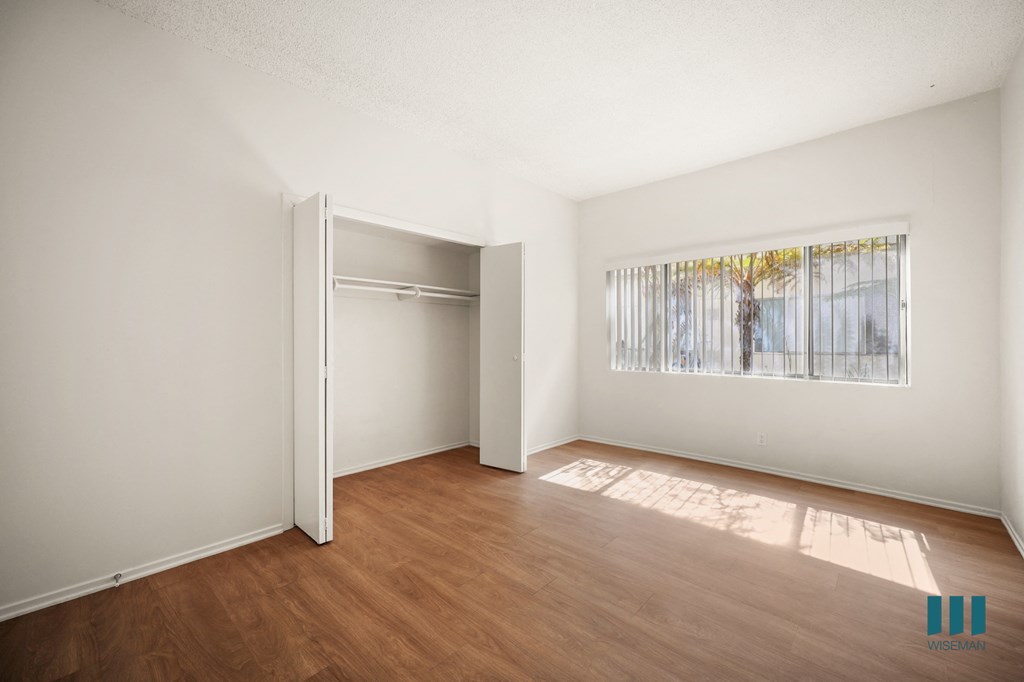 an empty living room with wood flooring and a door to a closet