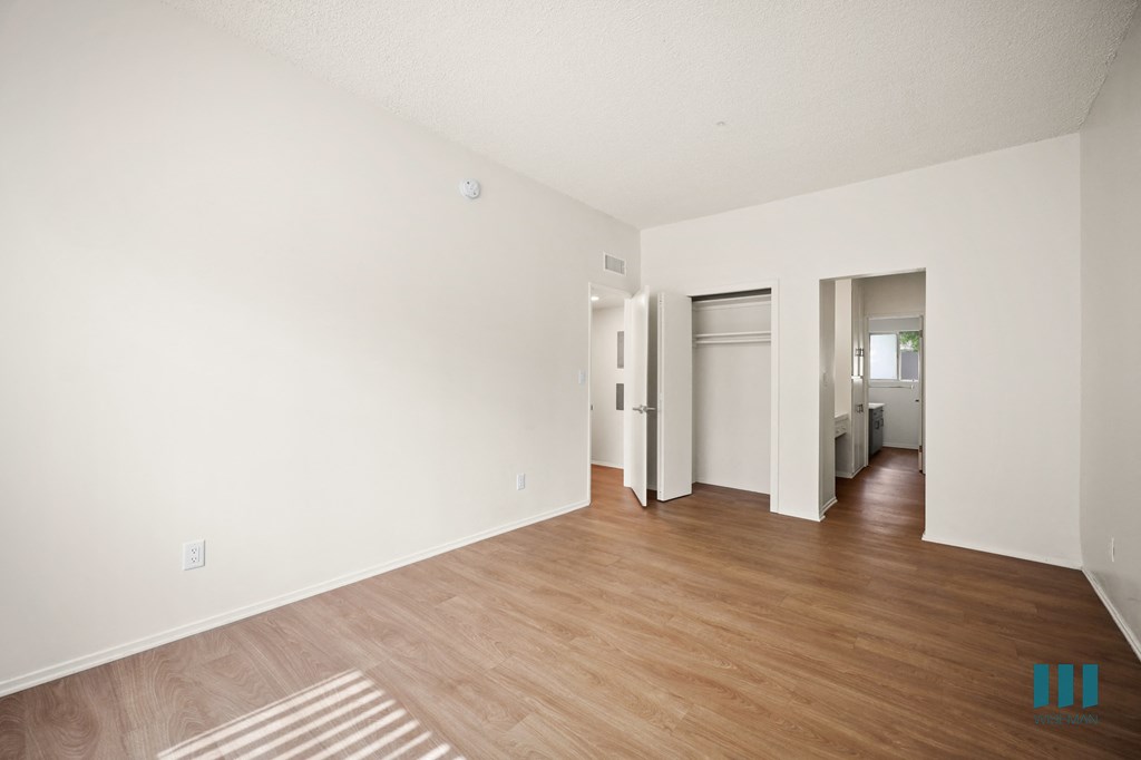 the living room and dining room of an apartment with white walls and wood floors