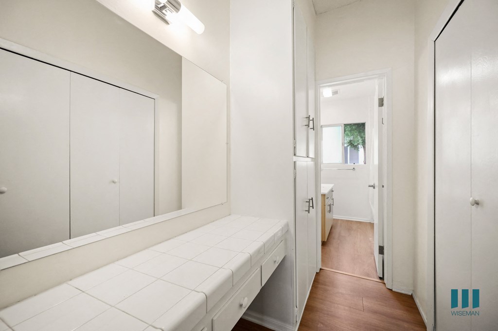 a white bathroom with a mirror and a white bench