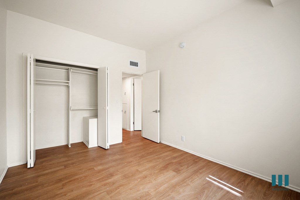 a bedroom with a wood floor and white walls and sliding closet doors