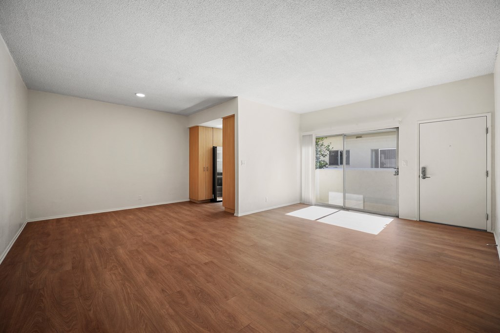 an empty living room with wood flooring and white walls