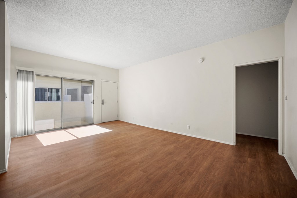 an empty living room with wood flooring and a sliding glass door