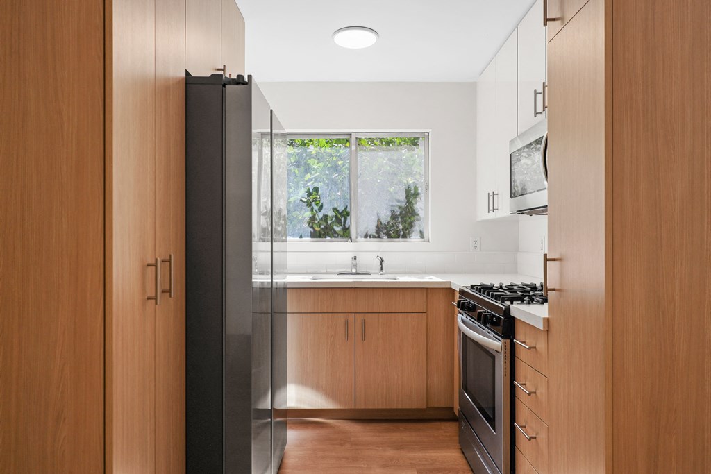 a kitchen with wooden cabinets and a stove and a window