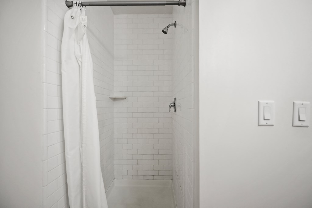 a white bathroom with a shower and a white shower curtain