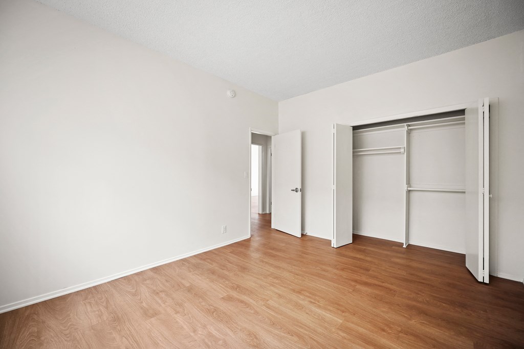 an empty room with wood floor and white walls and sliding closet doors