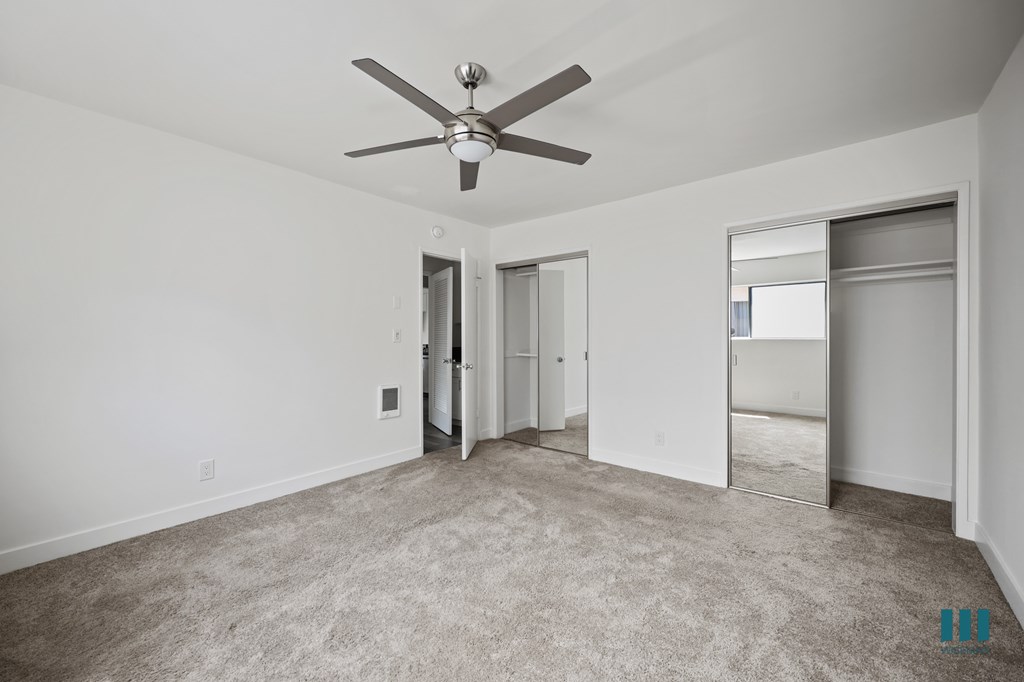 Bedroom with Two-Mirrored Closets, Ceiling Fan, and Carpet