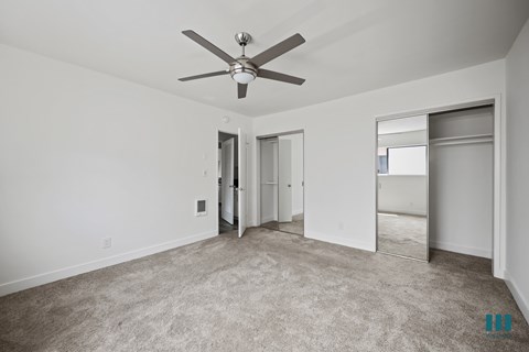 Bedroom with Two-Mirrored Closets, Ceiling Fan, and Carpet
