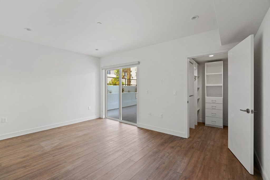 Bedroom with Walk-In Closet with Built-In Organizers, Vinyl Flooring, and Patio