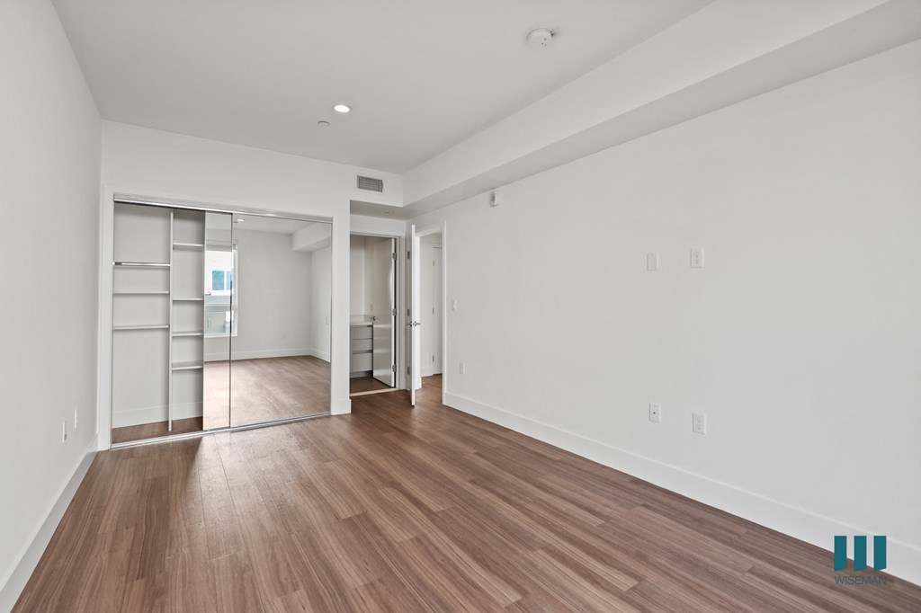 Bedroom with Mirrored Closet with Built-In Shelving, Recessed Lighting, and Vinyl Flooring