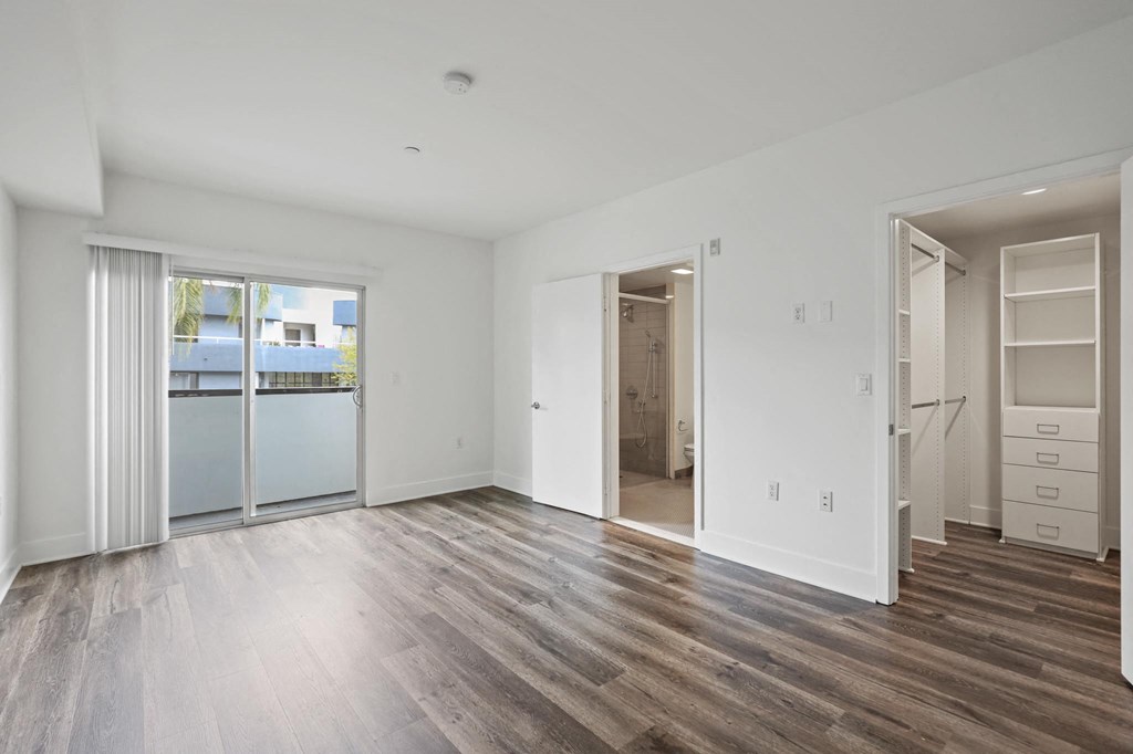 Bedroom with Walk-In Closet with Built-In Shelving, Bathroom, and Balcony