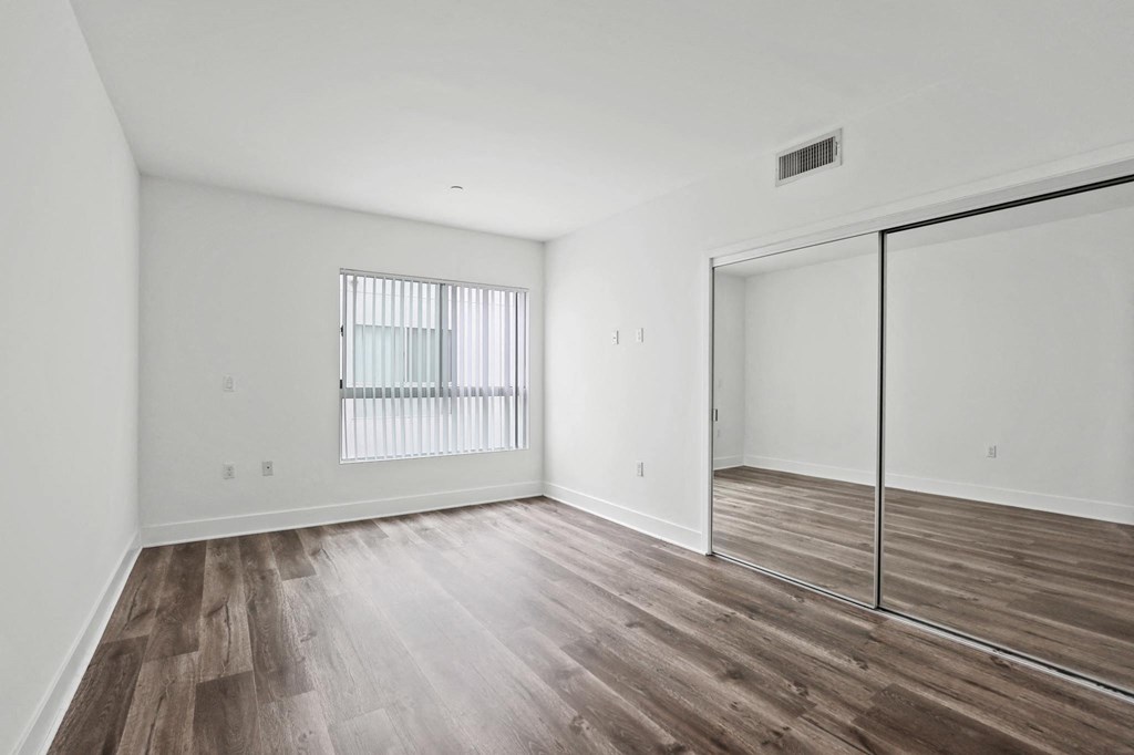 Bedroom with Mirrored Closet, Vinyl Flooring, and Windows