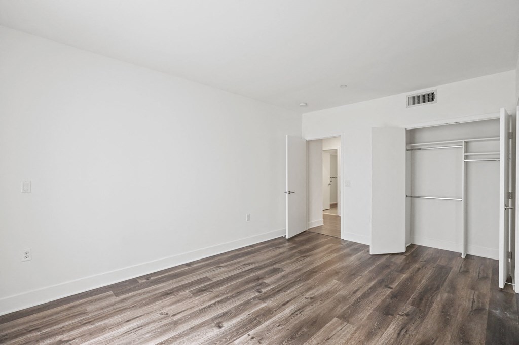 a bedroom with hardwood floors and white walls