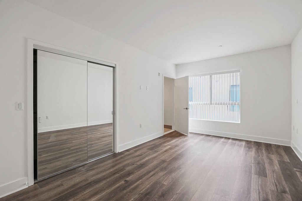 a bedroom with hardwood floors and white walls