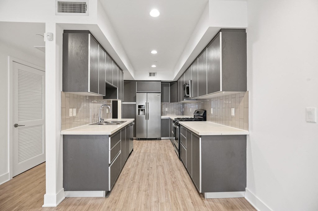 a kitchen with gray cabinets and white countertops
