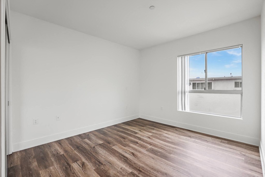 a bedroom with hardwood floors and a large window