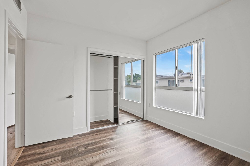 Bedroom with Mirrored Closet with Shelving, Vinyl Flooring, and Windows