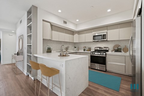 a kitchen with white cabinets and a white island with two chairs