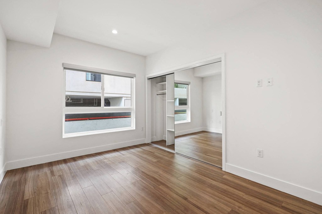 Bedroom with Mirrored Closet with Shelving, Large Windows, and Vinyl Flooring