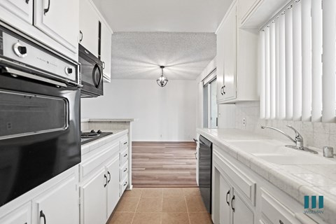 A kitchen with white cabinets and a black stove top oven.