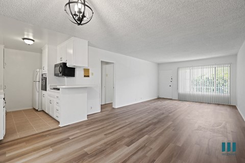 A spacious living room with wooden flooring and white walls.