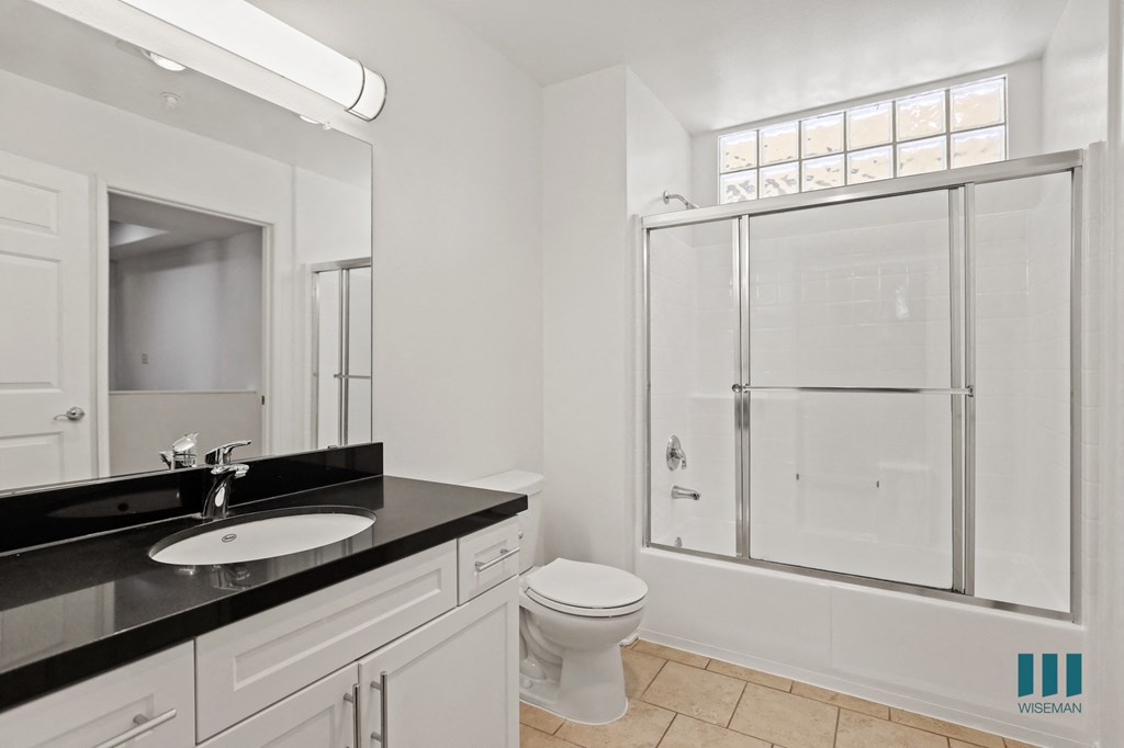 Bathroom with Full-Size Bathtub with Glass Door and Vanity Cabinet with Storage