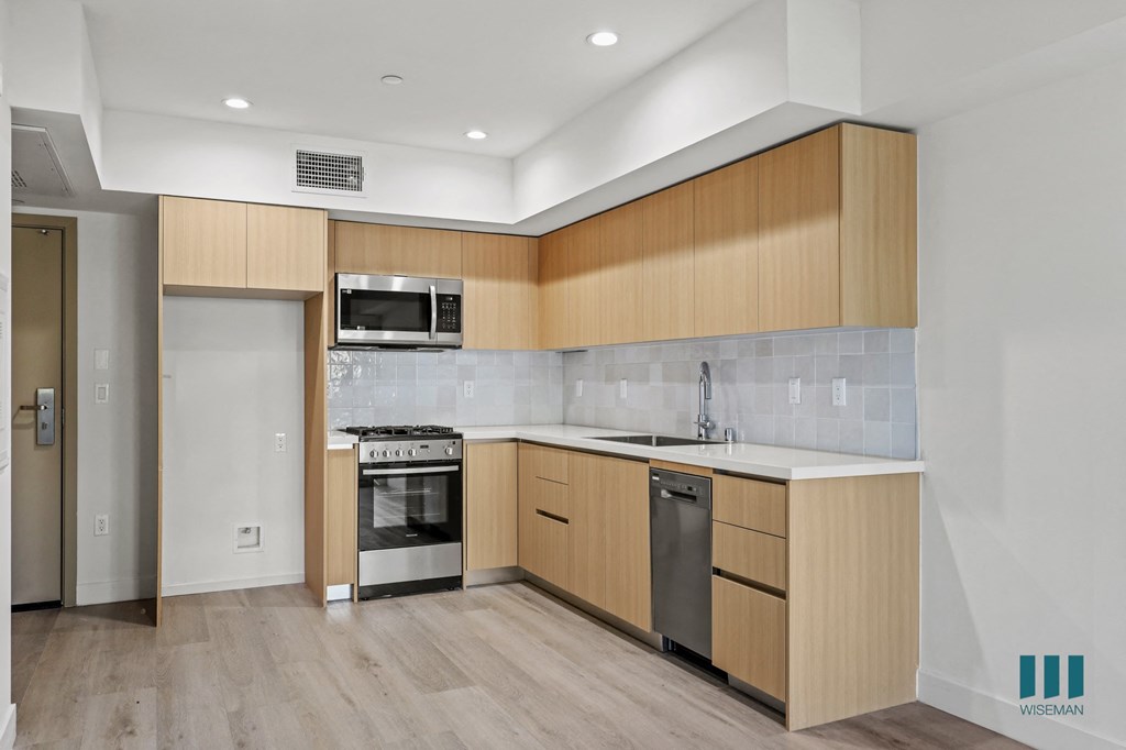 A kitchen with wooden cabinets and a stainless steel dishwasher.