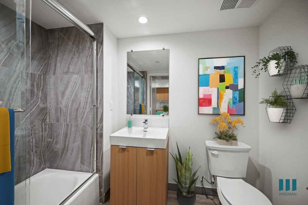 A bathroom with a white toilet, a sink, a mirror, and a potted plant.