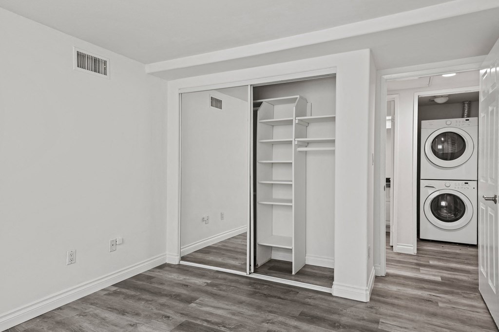 Bedroom with Closet with Shelving and an In-Suite Washer & Dryer Unit in the Hallway