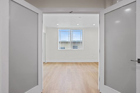 Double-Doors Leading to Bedroom Space with Window, Recessed Lighting, and Vinyl Flooring