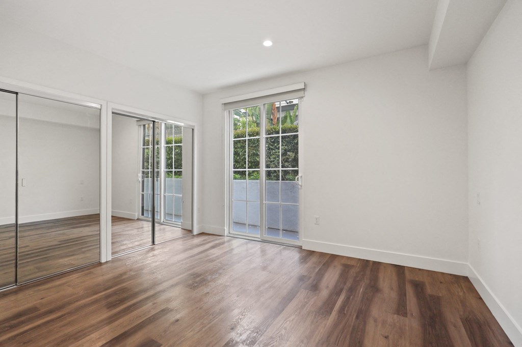 Bedroom with Double Mirrored Closets, Vinyl Flooring, and Balcony