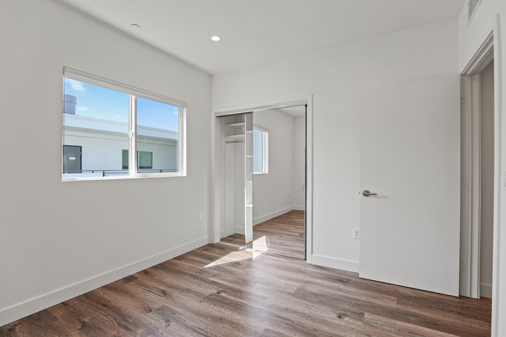 Bedroom with Mirrored Closet, Vinyl Flooring, and Window
