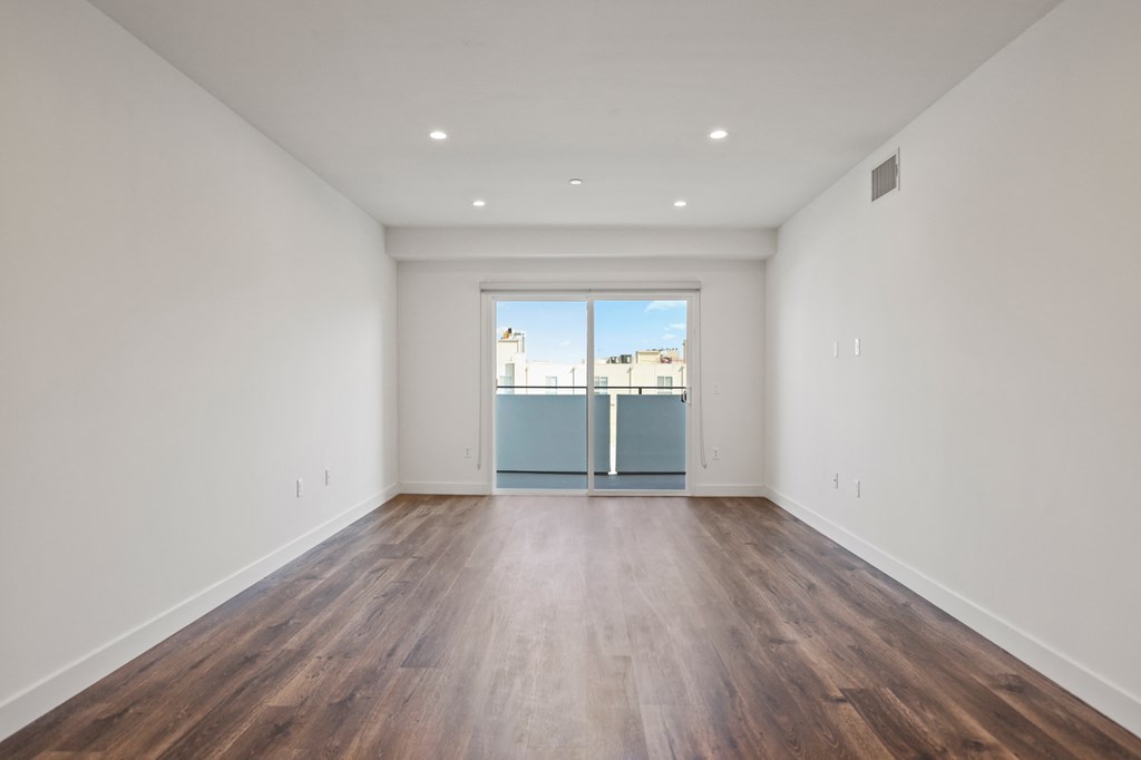 a bedroom with hardwood floors and white walls