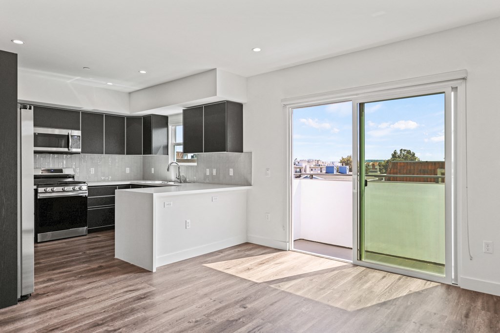 a kitchen and living room with a sliding glass door that leads to a balcony