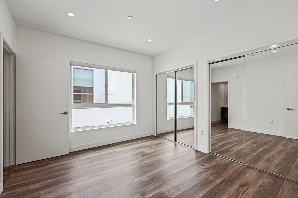 a bedroom with hardwood floors and white walls