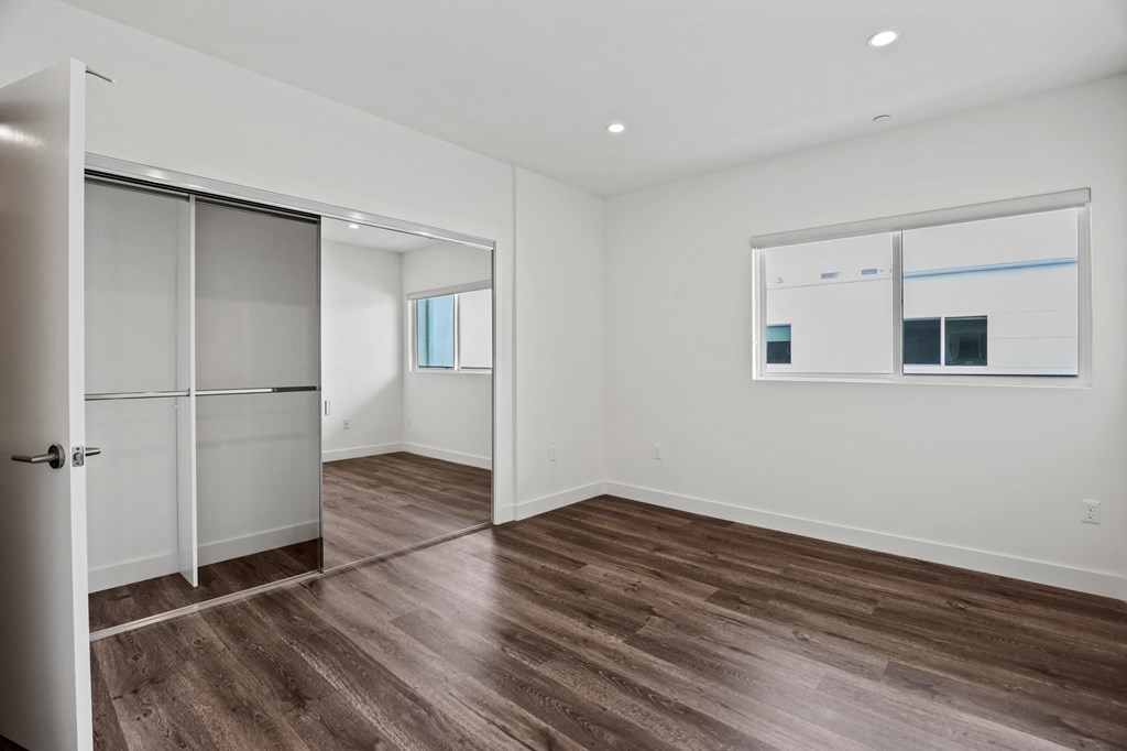 a bedroom with white walls and hardwood floors