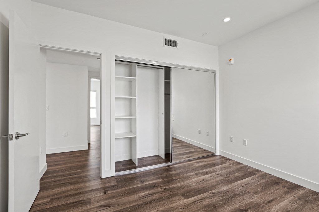 a bedroom with hardwood floors and white walls