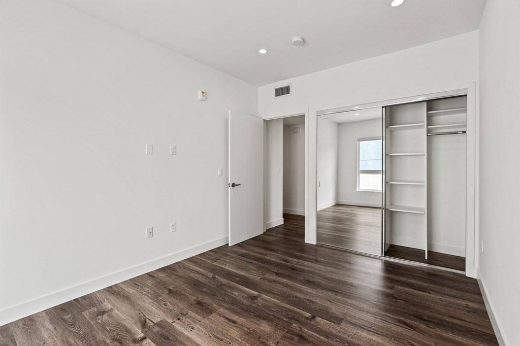 a bedroom with hardwood floors and white walls