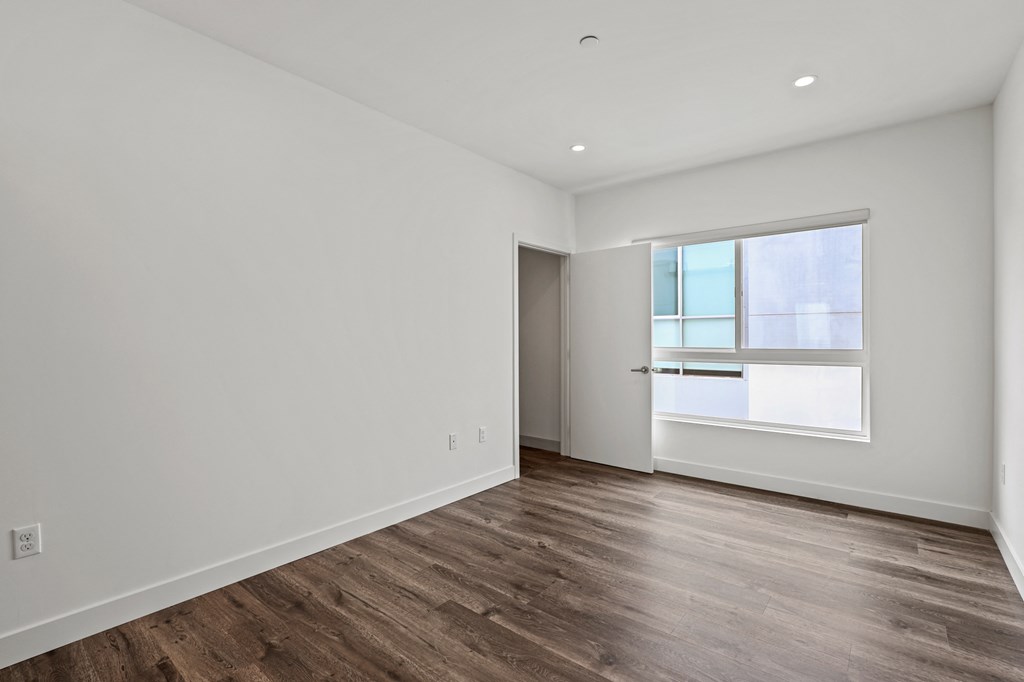 a bedroom with hardwood floors and white walls