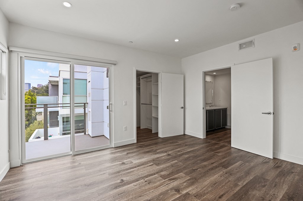a bedroom with hardwood floors and white walls