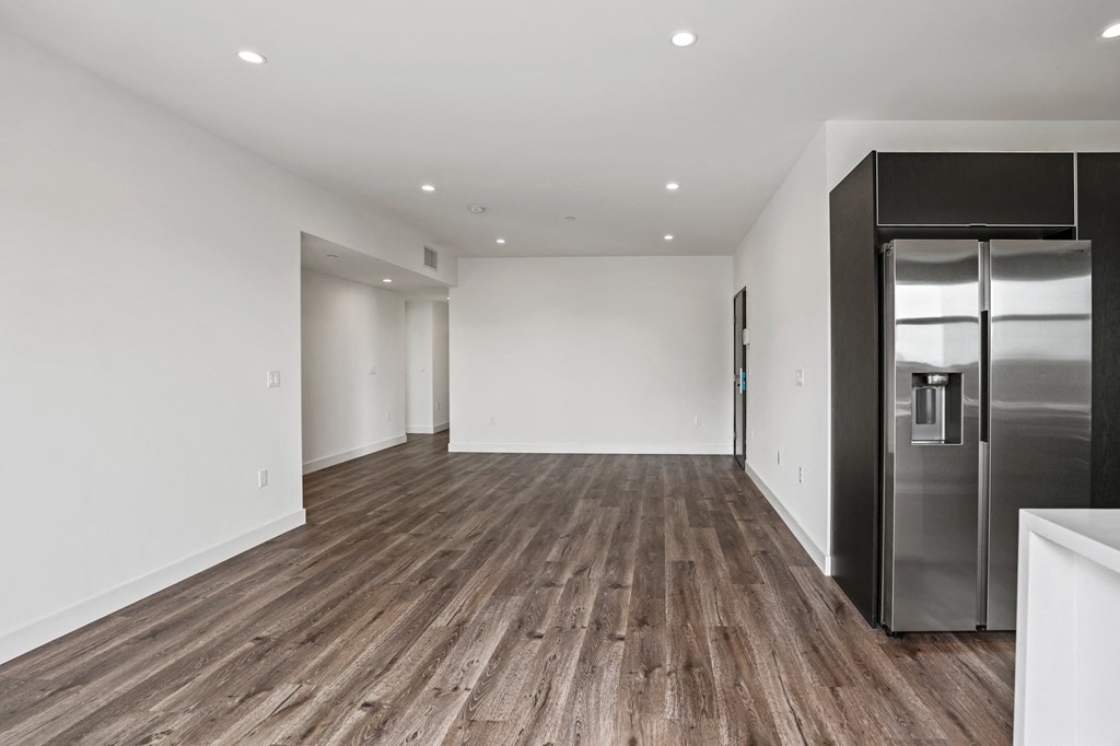 a kitchen and living room with white walls and a wooden floor