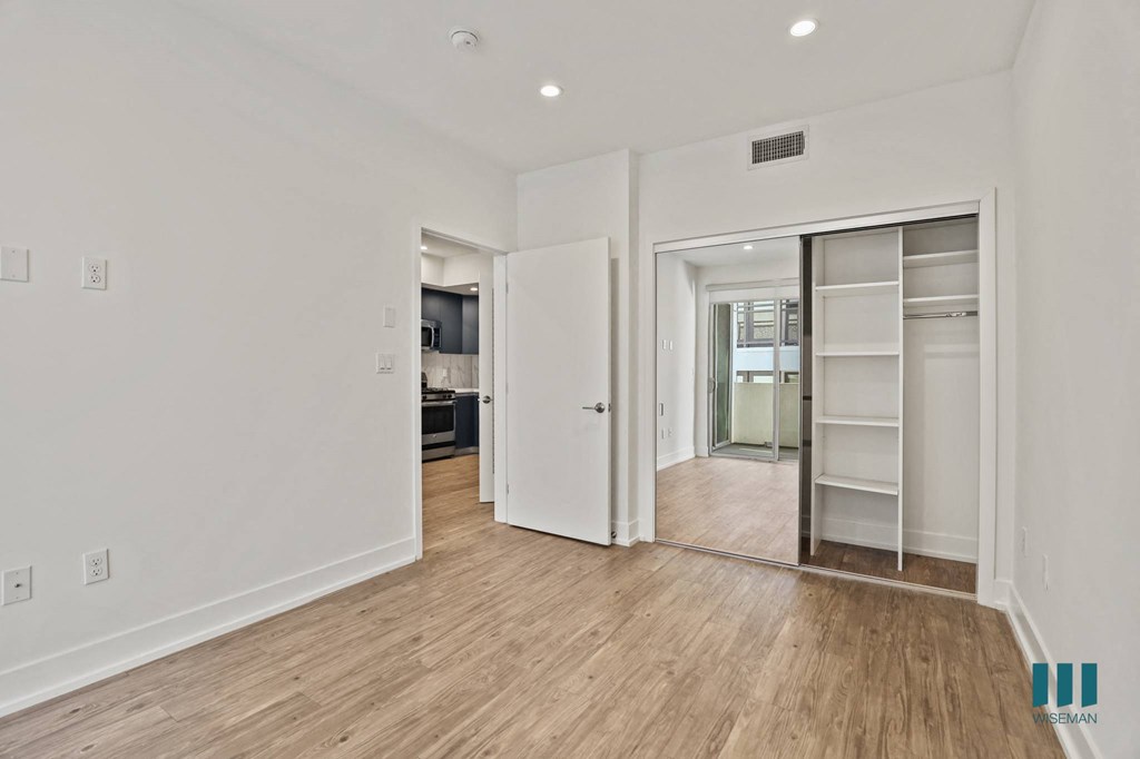 Bedroom with Closet with Built-In Shelving, Vinyl Flooring, and Recessed Lighting