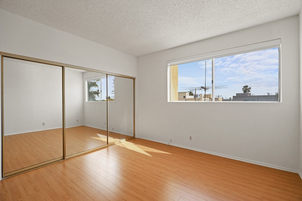 Bedroom with Large Mirrored Closet, Vinyl Flooring, and Windows