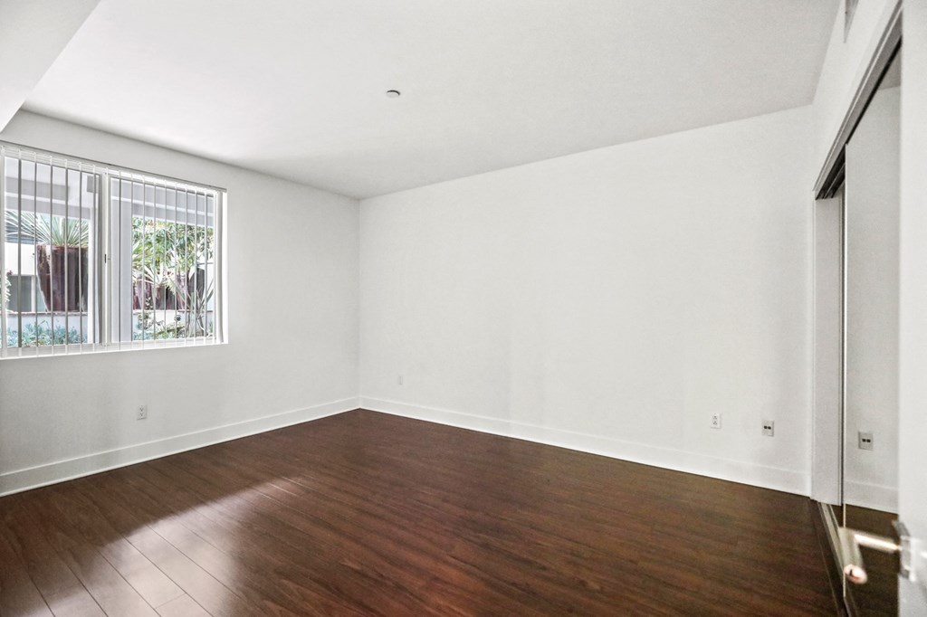 Bedroom with a Mirrored Closet, Vinyl Flooring, and Large Window